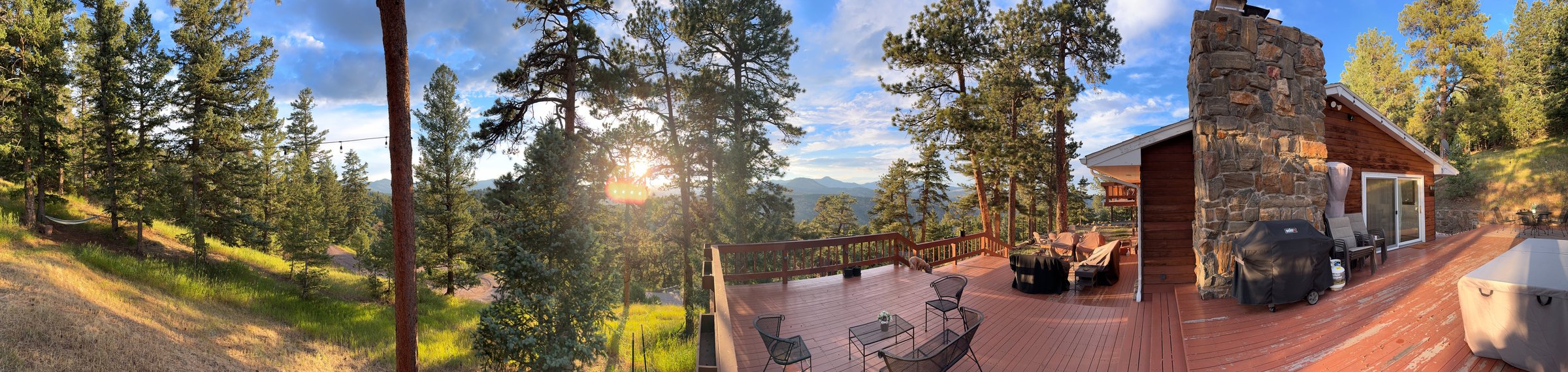 Panoramic view of the full deck, stone chimney, and surrounding pines