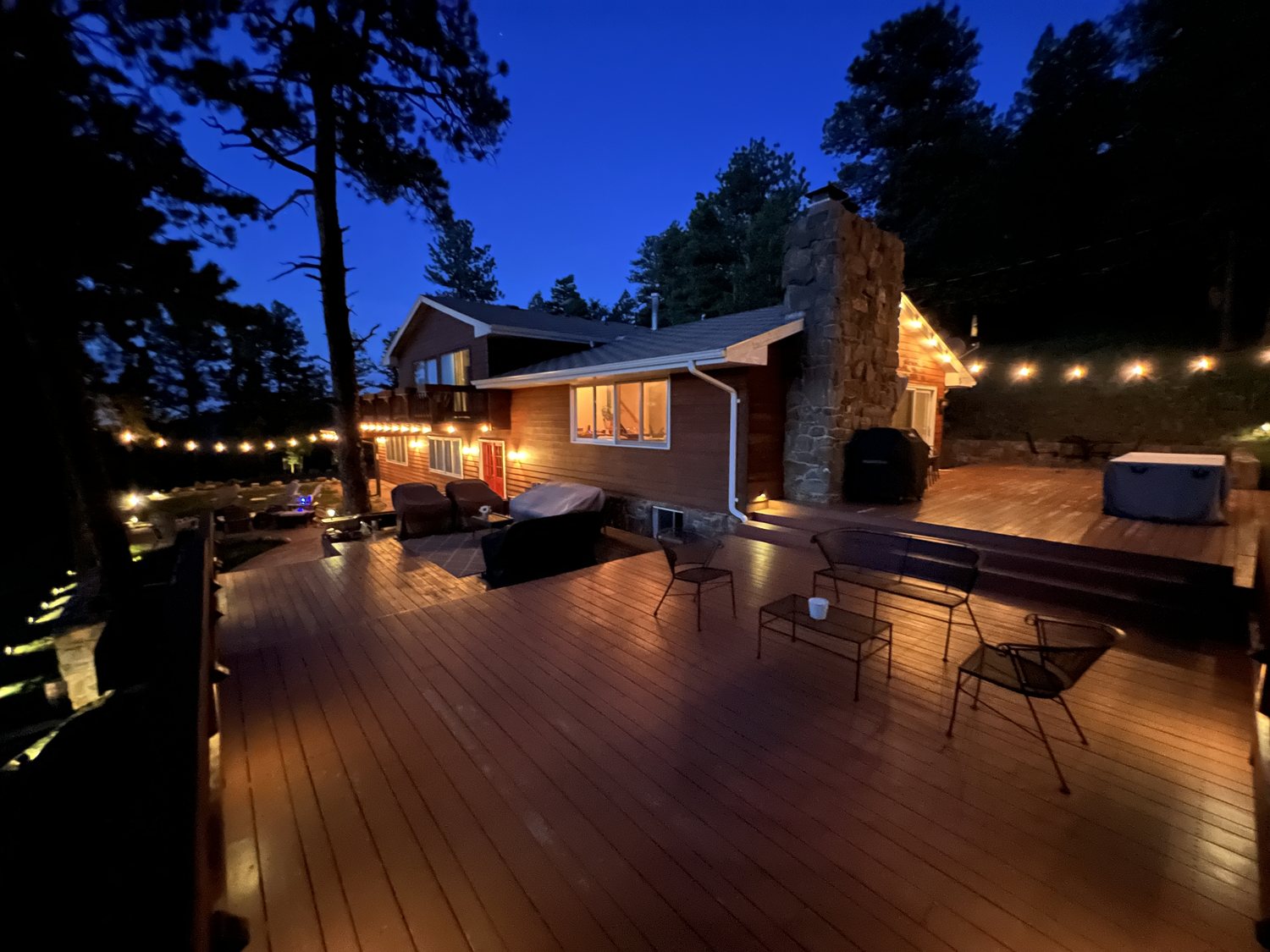 The house and deck lit with string lights at blue hour