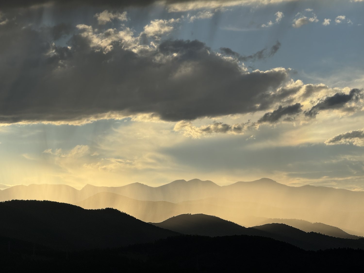Shafts of late light breaking through cloud over the foothills